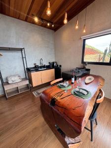 a room with a wooden table and a kitchen at Chalé Manacá in Sapucaí-Mirim