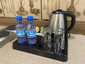 a tray with water bottles and glasses on a counter at فرويال للشقق المخدومة in Nughaylah