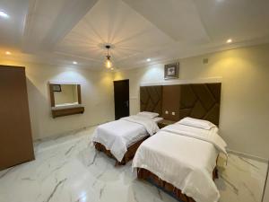 two beds in a room with marble floors at فرويال للشقق المخدومة in Nughaylah
