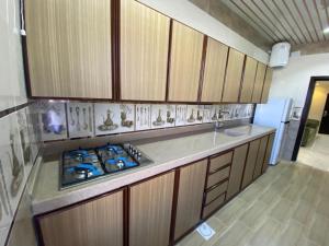 a kitchen with wooden cabinets and a stove top oven at فرويال للشقق المخدومة in Nughaylah