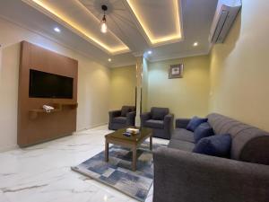 a living room with a couch and a tv at فرويال للشقق المخدومة in Nughaylah