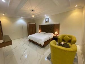 a hotel room with a bed and two chairs at فرويال للشقق المخدومة in Nughaylah +5 photos
