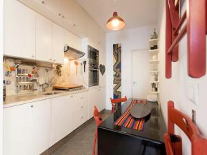 a kitchen with white cabinets and a table and red chairs at Pátio Alfama in Lisbon