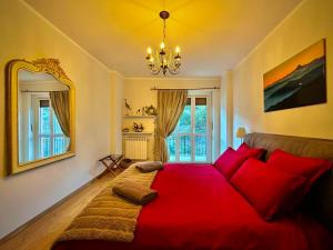 a bedroom with a bed with red pillows and a chandelier at Luxury 3 bedroom Grand Chalet in Perosa Argentina