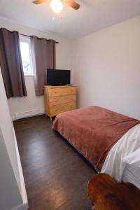 a bedroom with a bed and a dresser with a television at Mountain Joy Getaway in Valemount