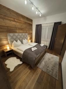 een slaapkamer met een groot bed met een houten wand bij Romantikapartment mit Wintercard in Ramsau am Dachstein