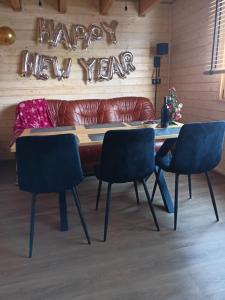 a table with two chairs and a couch with a happy new year sign at Winnica Zatorska in Olszyny