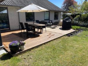 a wooden deck with a table and an umbrella at Skovbrynets guesthouse in Herning