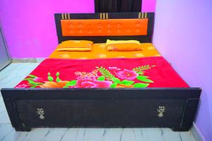 a black bed with a red blanket and flowers on it at Mahakal homestay in Ayodhya