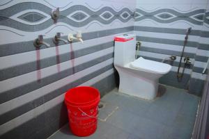 a bathroom with a toilet and a red bucket at Mahakal homestay in Ayodhya