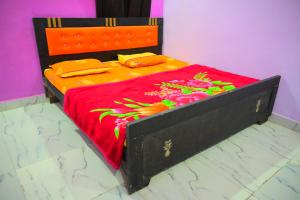 a bed with a red bedspread with flowers on it at Mahakal homestay in Ayodhya +15 photos