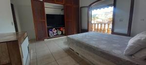 a bedroom with a bed and a balcony with a television at Suíte da Virada in Guarujá