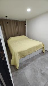 een bed in een kleine kamer met een gele deken erop bij Depto Roko in Villa Gesell
