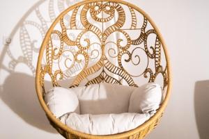 a basket chair with white pillows in a room at les doux secrets de Bergère in Périgueux