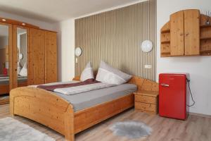 a bedroom with a wooden bed and a red refrigerator at Botenwirt - Self Check in in Spital am Pyhrn
