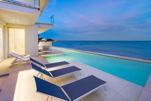 una casa con piscina con sedie e oceano di Bedda Matri a Noto