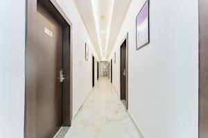 a corridor with white walls and a hallway with black doors at Treebo Advantage Inn in Allahābād