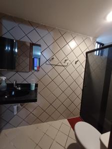 a tiled bathroom with a sink and a toilet at Apartamento Cobertura Praia Camboinha in Cabedelo
