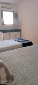 two beds in a room with a window at Kitnets Caribe Maragogi Peroba in Maragogi
