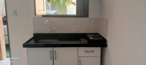 a small kitchen with a sink and a mirror at Kitnets Caribe Maragogi Peroba in Maragogi