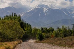 a dirt road with a snow covered mountain in the background at Om infinity - Soft opening in Tupungato