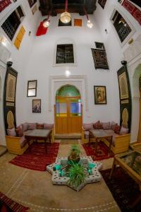 a living room with a table and chairs in a room at Shauala Riad - Where History Lives in Fès