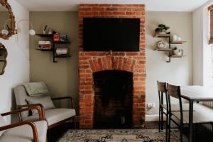 a living room with a brick fireplace with a flat screen tv at River Cottage in Beccles