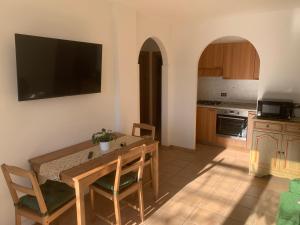 eine Küche mit einem Holztisch und einem TV an der Wand in der Unterkunft Appartamento Ape Verde in Piano dʼArta