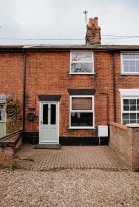 a brick house with a white door and windows at River Cottage in Beccles
