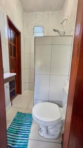 a bathroom with a white toilet and a blue rug at Taboca Chalé na Rua do Serrão in Cairu