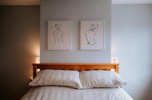 a bedroom with two drawings on the wall above a bed at River Cottage in Beccles