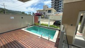 a swimming pool on a deck next to a building at Cód 2 - Cobertura de 2 dormitórios na Praia Grande in Rodeio