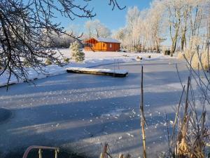 een met sneeuw bedekt veld met een rode schuur op de achtergrond bij Pond Cabin 