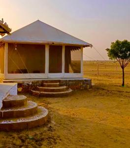 een gebouw met trappen in een veld met een boom bij K R Desert Resort in Dedha