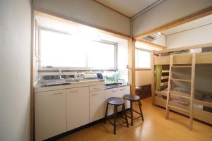 a small kitchen with a sink and two stools at Guesthouse Oasis in Osaka