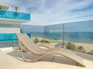 eine Holzbank auf einem Balkon mit Blick auf den Strand in der Unterkunft Hotel Continental in San Benedetto del Tronto