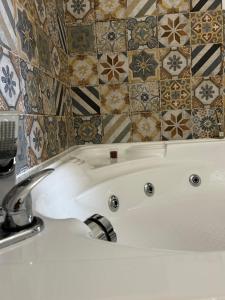 a bathroom with a tub and a tile wall at Sogno Mediterraneo in Formia