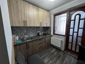 eine Küche mit Holzschränken, Spüle und Fenster in der Unterkunft George's Apartaments in Donduşeni