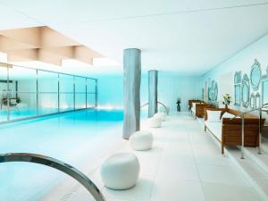 een groot zwembad met witte meubels in een gebouw bij Hôtel Le Royal Monceau Raffles Paris in Parijs