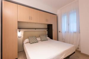 a small bedroom with a white bed and cabinets at Residence Perla in Misano Adriatico