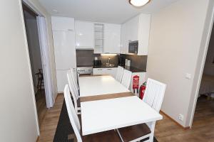 a white kitchen with a white table and chairs at Cozy Alpine-Style Apartment in the Heart of Levi with Private Sauna & Fireplace in Levi