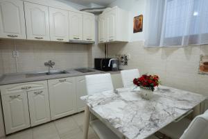 una cucina con armadi bianchi e un tavolo con fiori di Villa Alice a Suceava