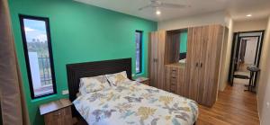 a bedroom with a bed and a green wall at The Retreat Apartment in Nadi
