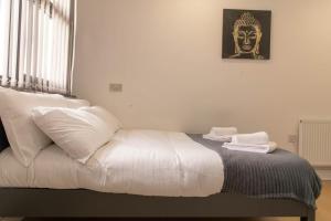 un letto con cuscini bianchi e l'immagine di una maschera di Convenient Budget Sunderland Studio with Views a Sunderland