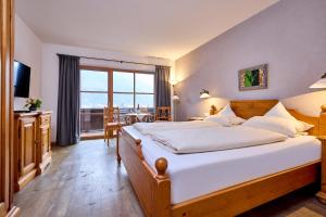 une chambre avec un grand lit et une grande fenêtre dans l'établissement Landhaus Sonnenbichl Mittenwald, à Mittenwald