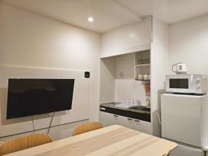 a kitchen with a table and a microwave and a refrigerator at Hermitage Hotel Nishishin in Tokyo