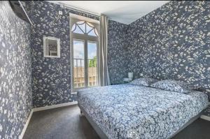 una camera da letto con pareti blu, un letto e una finestra di Le Seysses a Seysses