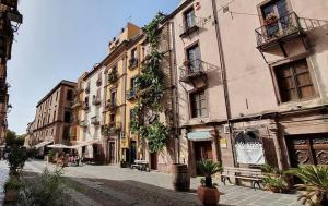 una strada cittadina vuota con edifici e piante di Le Stanze Della Castellana a Bosa