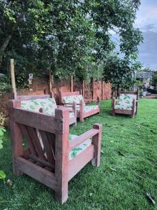 drie houten banken die in het gras op een veld staan bij CHÁCARA dos CHEIROS in Atibaia