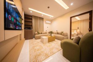 a living room with couches and a flat screen tv at Revana for families in Jeddah